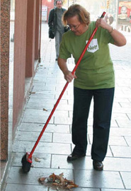 Foto decorativa. Imagen de una mujer barriendo su trozo de acera