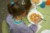 Nena d'esquenes dinant al menjador d'un centre escolar 