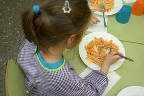 Nena d'esquenes dinant al menjador d'un centre escolar 